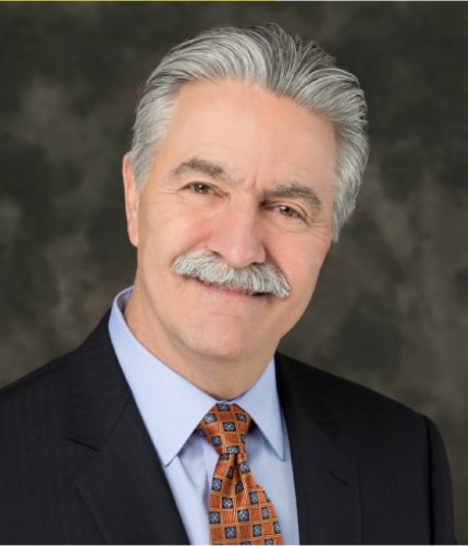 close up headshot of an older man with a mustache in suit smiling